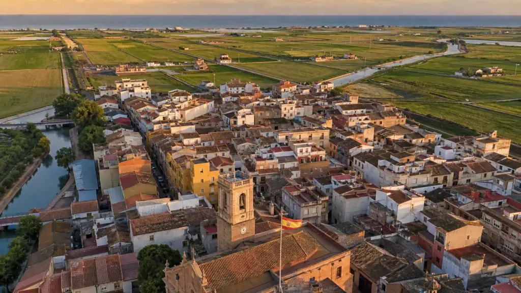 enric masip: vista aérea de un pueblo valenciano rodeado de arrozales al atardecer
