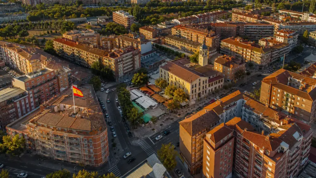 gasto de los hogares: vista aérea de un barrio residencial español con edificios de viviendas y un pequeño mercado