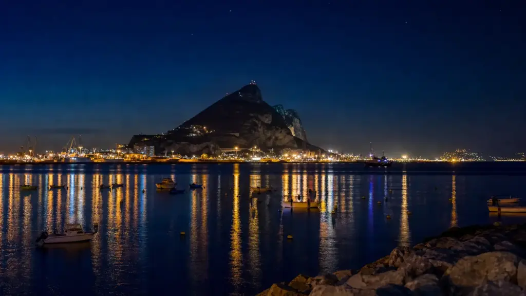atlántida en gibraltar: puerto iluminado de noche junto al estrecho, con el peñón recortado sobre el mar oscuro