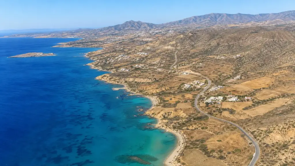 comisión de derechos humanos: vista aérea de la costa de Chipre con mar turquesa, colinas secas y pueblos blancos