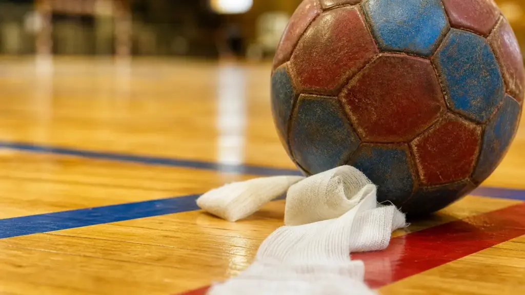 barça de balonmano: balón de cuero junto a una venda sobre el parqué con líneas azulgranas