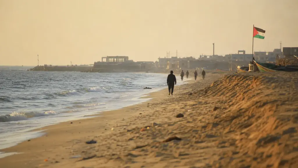 playa de gaza: costa arenosa del norte de la Franja al atardecer con figuras lejanas de espaldas junto al mar