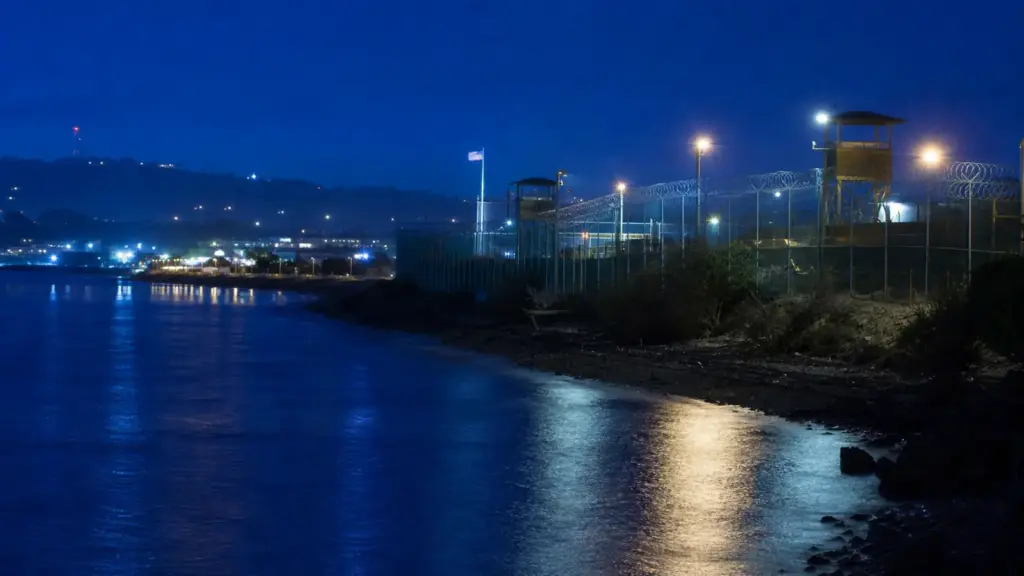 cierre de guantánamo: vista nocturna de un recinto vallado e iluminado por reflectores junto al mar
