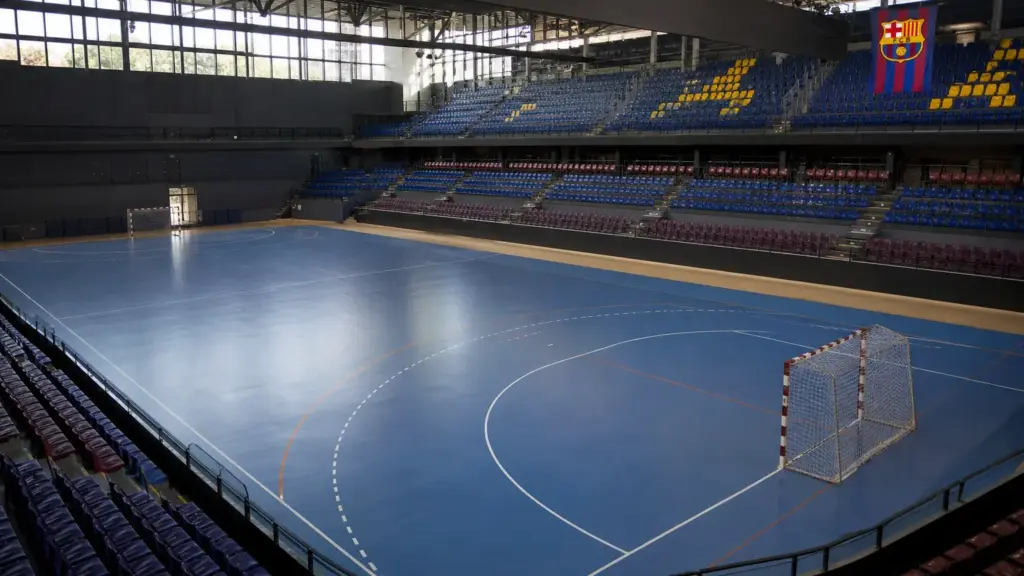 barcelona cifec en torrevieja: pabellón de balonmano vacío con porterías y una bandera azulgrana en las gradas