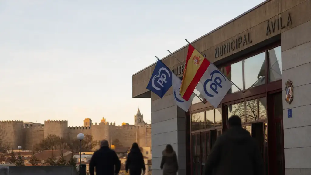 acebes en ávila: exterior de un polideportivo con banderas del PP y de España y las murallas de la ciudad al fondo