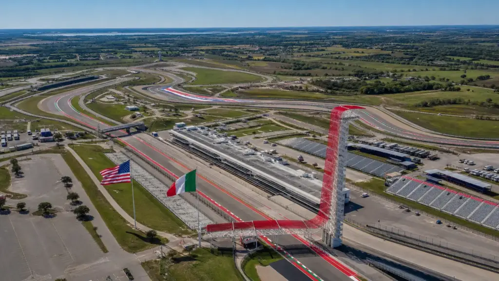 antonelli en austin: vista aérea de un circuito de carreras en Texas con tribunas y banderas de Estados Unidos e Italia bajo el sol