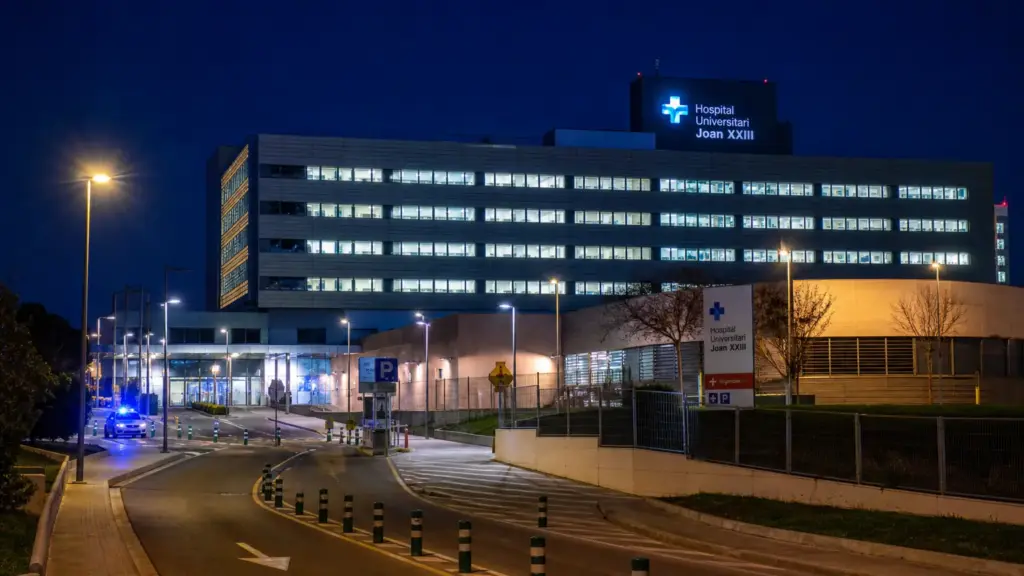 hospital joan xxiii: edificio hospitalario de noche con ventanas iluminadas y un coche policial en el acceso