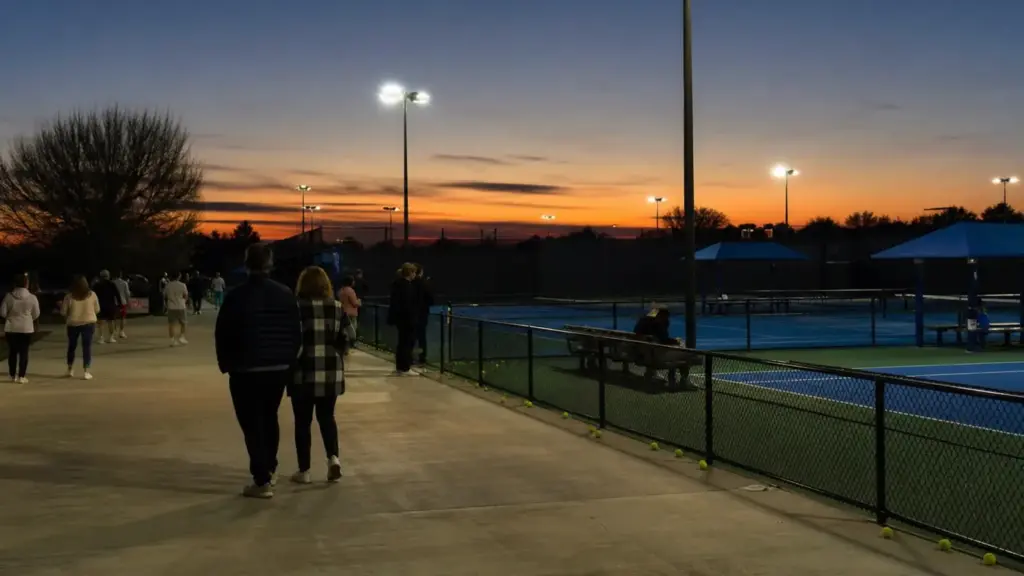davidovich y jódar: pistas de tenis azules iluminadas al atardecer con espectadores lejanos de espaldas