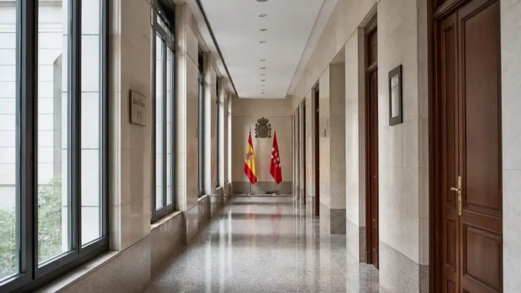 gonzález amador: pasillo amplio y vacío de unos juzgados de Madrid con las banderas de España y de la Comunidad de Madrid