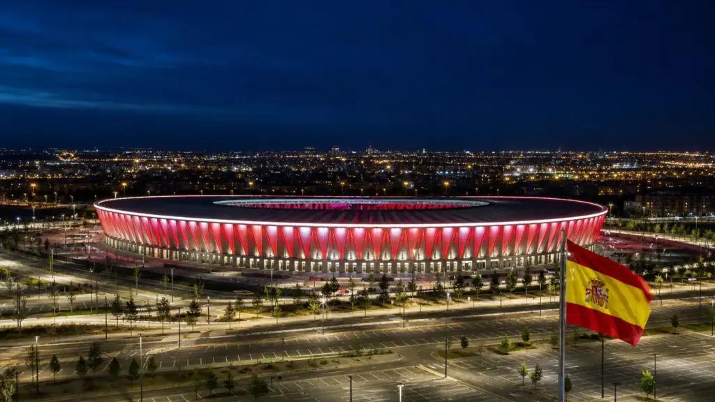 multa al barcelona: estadio de fútbol iluminado de noche con una bandera de España y las luces de la ciudad al fondo
