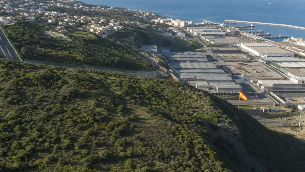 migrantes en ceuta: vista aérea de montes, naves industriales y barrios junto a la frontera del Tarajal