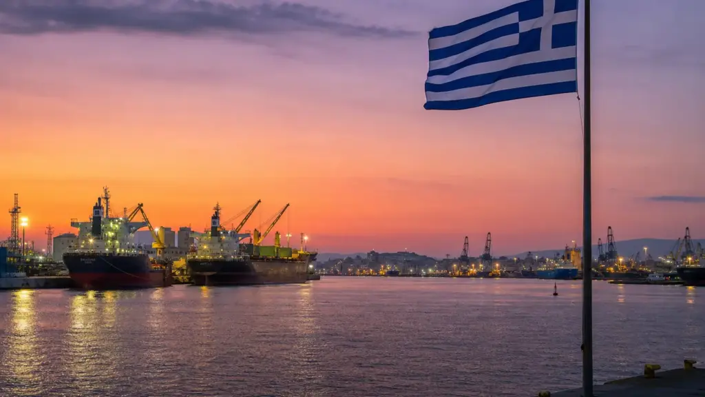 giorgos vardinogiannis: puerto de El Pireo al atardecer con buques mercantes y una bandera de Grecia