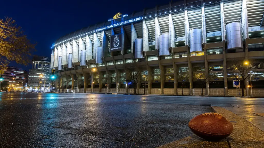 tom gabarró: estadio Bernabéu iluminado de noche en Madrid con un balón de fútbol americano en primer plano