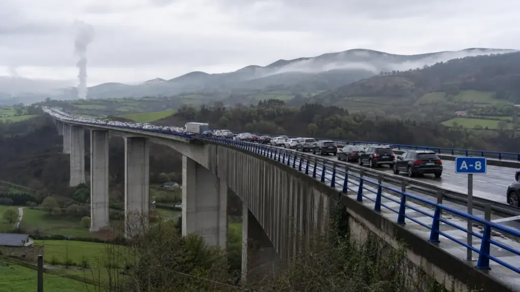 viaducto de somonte: autovía elevada sobre un valle verde con una larga fila de coches detenidos y humo a lo lejos