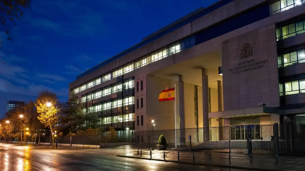hacienda cuatro céntimos: edificio de oficinas con ventanas iluminadas y bandera de España de noche