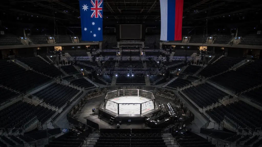 ufc 333: octágono vacío iluminado en un estadio cubierto de Abu Dabi con banderas de Australia y Rusia
